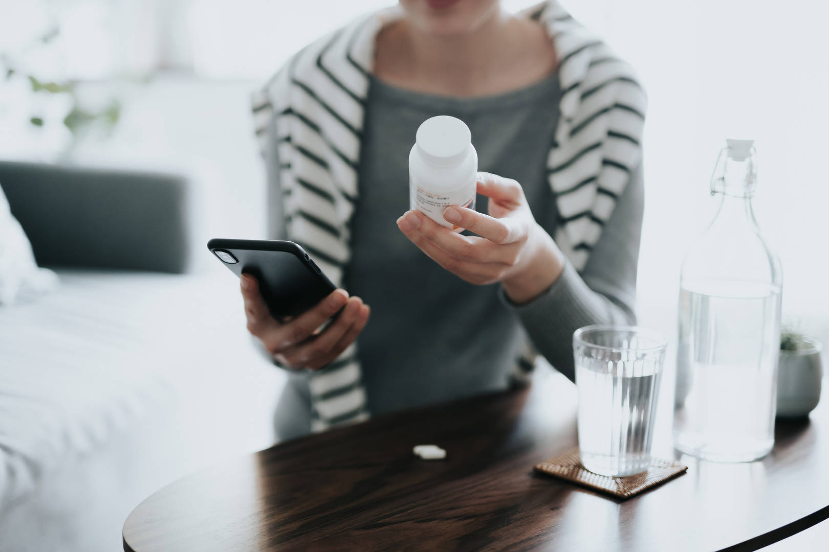 Woman looks at pill bottle and her phone