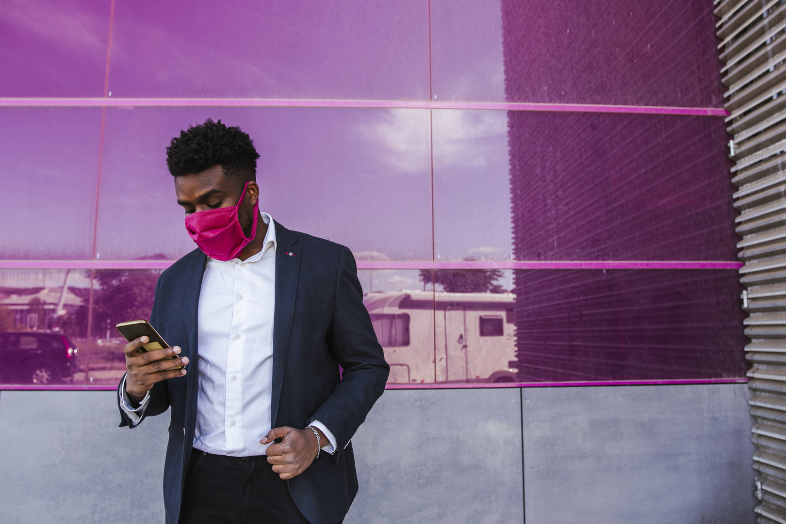man wearing pink mask using mobile phone
