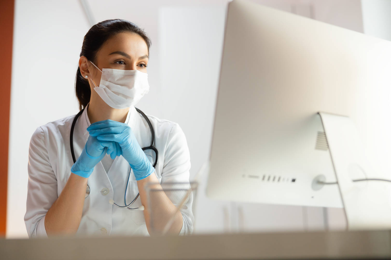 Masked healthcare professional watching computer
