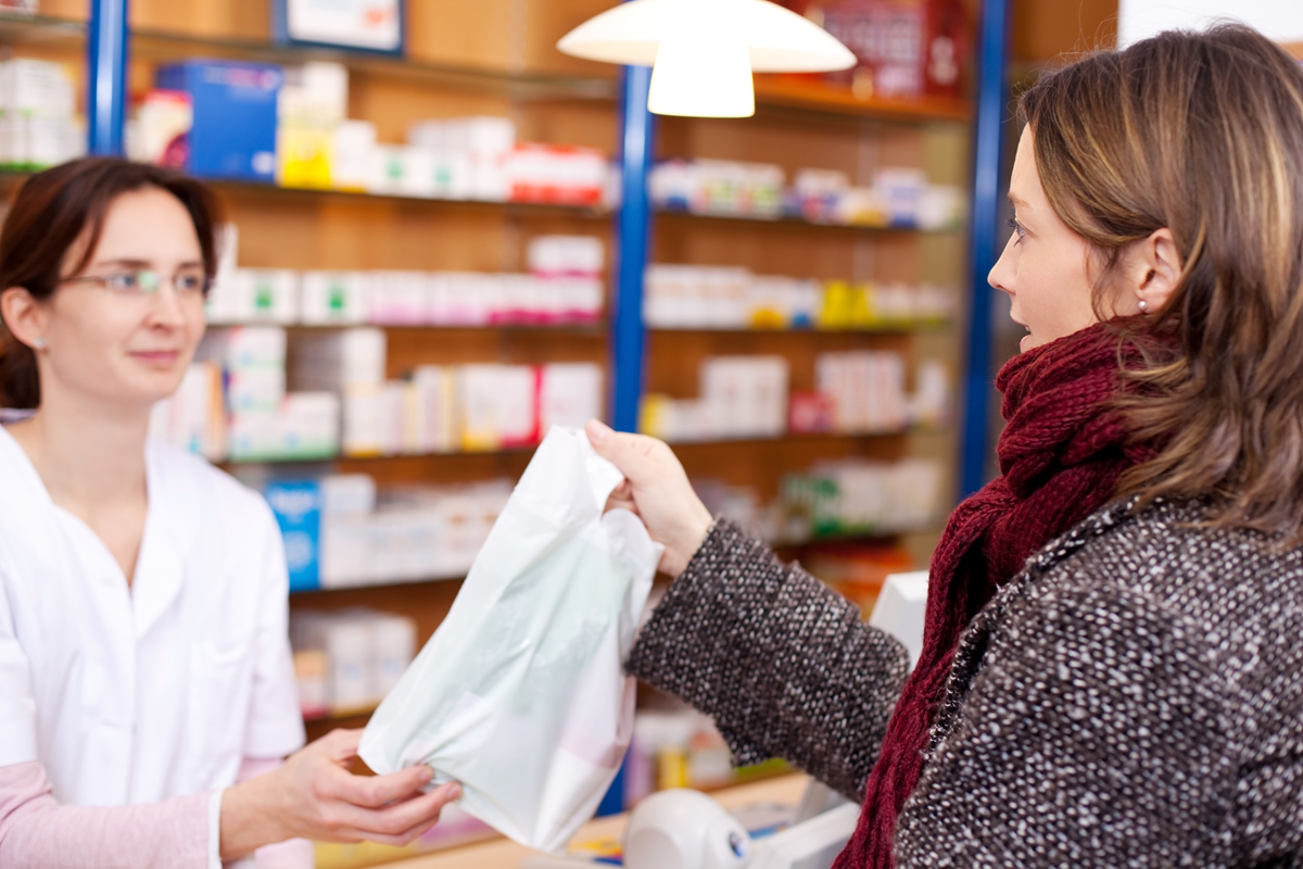 A pharmacist handing a bag with prescriptions in it to a patient