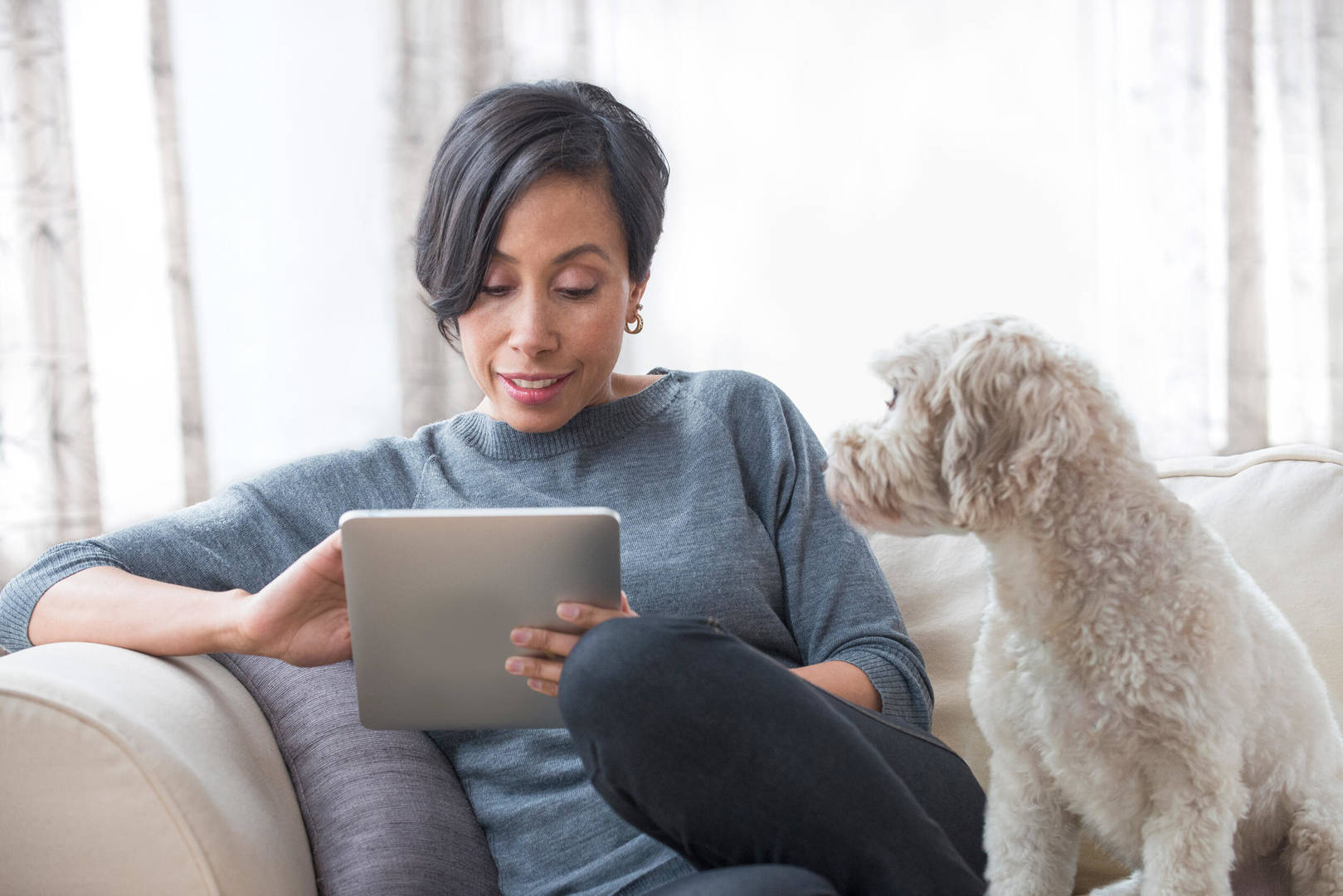 Black woman with small dog looks at tablet
